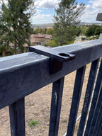 Drop-style fence clip mounted on a metal fence rail, showing the post-mount hole — Groovy Lanterns