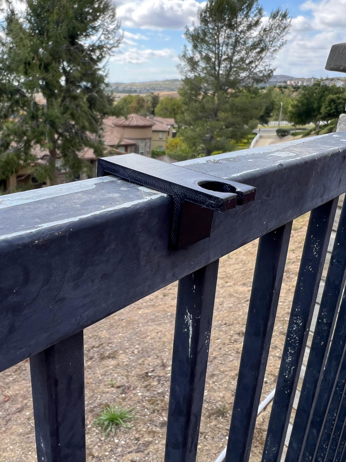 Drop-style fence clip mounted on a metal fence rail, showing the post-mount hole — Groovy Lanterns