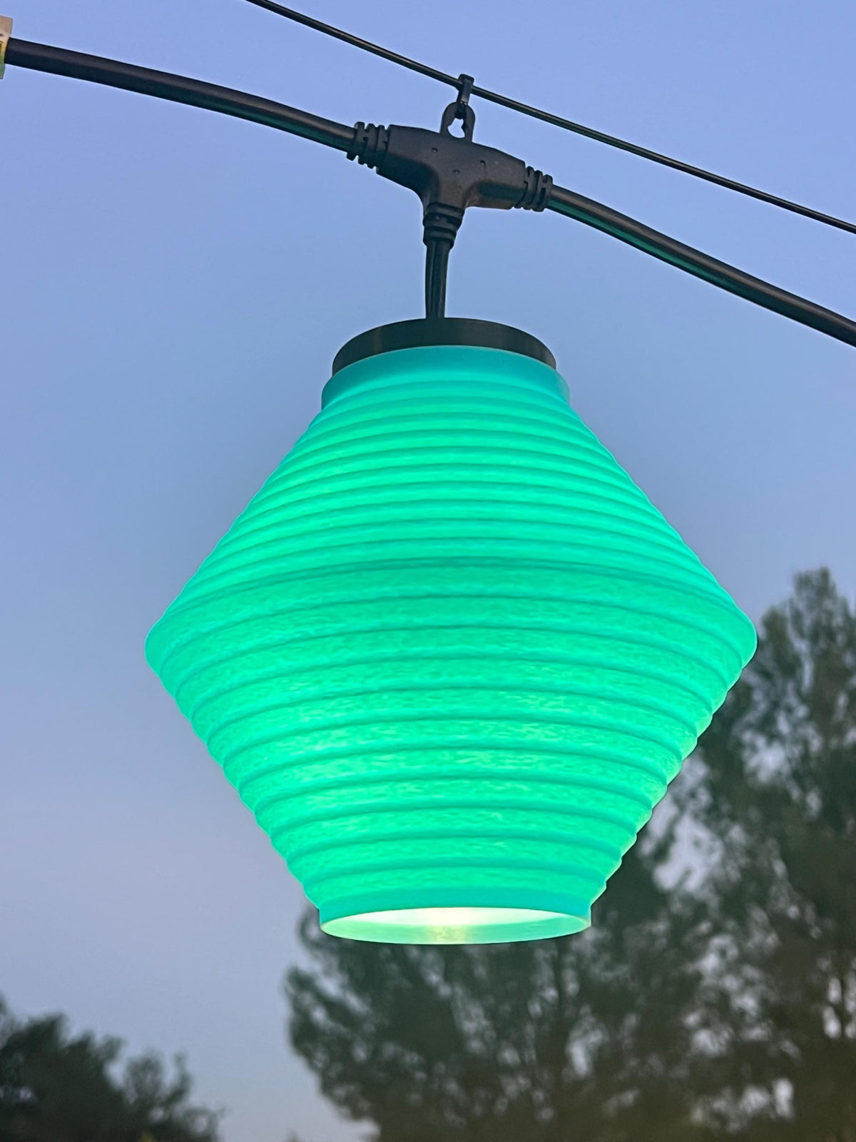 The Wisp lantern cover glowing green at dusk — Groovy Lanterns