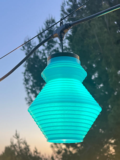 The Tumble lantern cover glowing teal at dusk — Groovy Lanterns