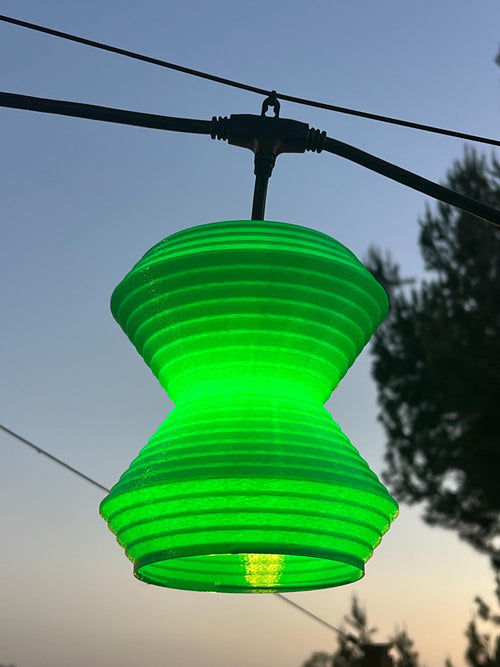 The Whirl lantern cover glowing green at dusk — Groovy Lanterns